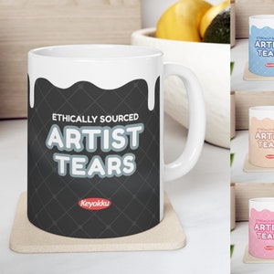 May include: White ceramic mug with a black and white design. The mug has a dripping white glaze and says "Ethically Sourced Artist Tears" in gray text with a red "Keyokku" logo.