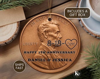 May include: A round copper-colored ornament featuring the profile of Abraham Lincoln, the text IN GOD WE TRUST, LIBERTY, 8-18-2019 inside a heart, HAPPY 7TH ANNIVERSARY, and DANIEL & JESSICA. The ornament hangs from a gold string.