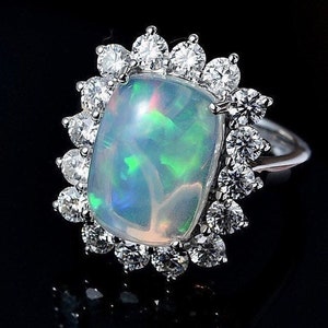 Könnte beinhalten: Ein silberner Ring mit einem großen, ovalen Opal-Edelstein, der von einem Heiligenschein aus kleineren Diamanten umgeben ist.
