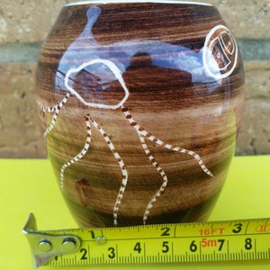Peut inclure: Un vase en céramique brun avec des motifs abstraits blancs. Le vase mesure 15 cm de haut et a une forme arrondie.