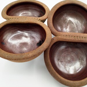 May include: Set of four brown ceramic bowls with a reddish-brown glaze. The bowls are connected together in a unique design.
