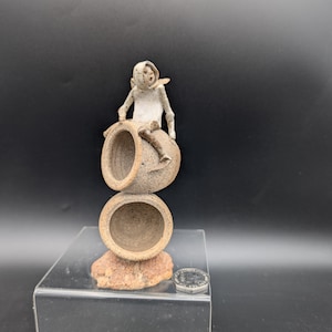 Graham Piggott Bladon Cardman-figur sittande på två tunnor