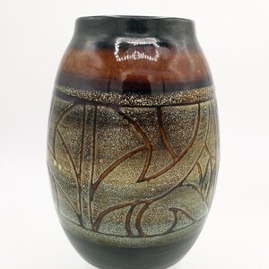 May include: A brown and black ceramic vase with a geometric design. The vase has a rounded shape and a textured surface.