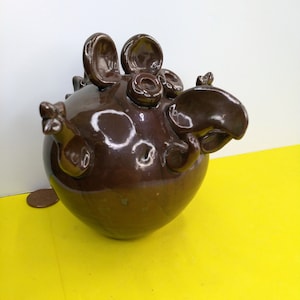 May include: A brown ceramic piggy bank with large ears, a long nose, and a round body. The piggy bank has a glossy finish.