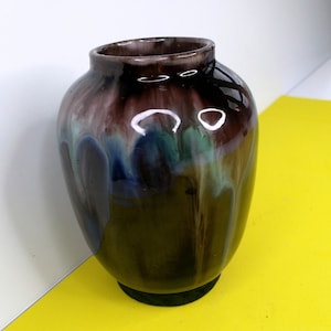 May include: A small, round ceramic vase with a dark brown glaze and streaks of blue, green, and white.