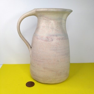 May include: A white ceramic pitcher with a pink and gray marbled glaze. The pitcher has a wide mouth and a handle.