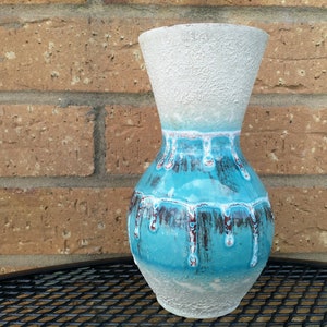 May include: A blue and white ceramic vase with a textured finish and a drip glaze design. The vase has a wide mouth and a rounded body.