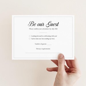May include: A white RSVP card with black text that reads "Be our Guest". The card has a line for guests to confirm their attendance by July 25th and a checkbox for guests to indicate whether they are looking forward to celebrating or are sad to miss out. There is also a space for guests to indicate the number of guests attending and any dietary requirements.