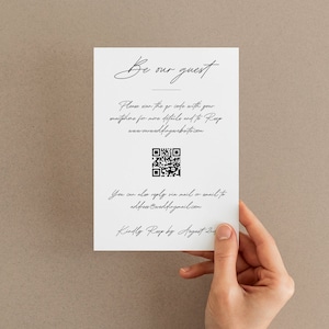 May include: A white card with black text that reads "Be our guest". The card includes a QR code and the text "Please scan the QR code with your smartphone for more details and to RSVP www.ourweddingwebsite.com You can also reply via mail or email to address@email.com Kindly RSVP by August 2nd"