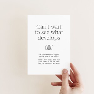 May include: A white card with black text that reads "Can't wait to see what develops."  A small black and white camera icon with a heart inside is below the text.  The text below the icon reads "Use this camera to capture special pics of our night. Take a few snaps, then pass it on. Leave it on the table then the exposures are gone."
