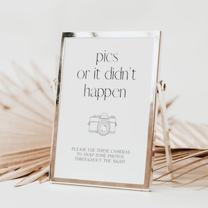 May include: A silver picture frame with a white background and black text that reads "pics or it didn't happen". A black and white illustration of a camera is below the text. The text below the camera reads "Please use these cameras to snap some photos throughout the night."