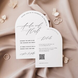 May include: A white wedding invitation with a modern arch design. The invitation features the names "Anchir and Hulk" in elegant calligraphy. The text includes the date, time, and location of the wedding. A QR code is included for guests to access additional details.