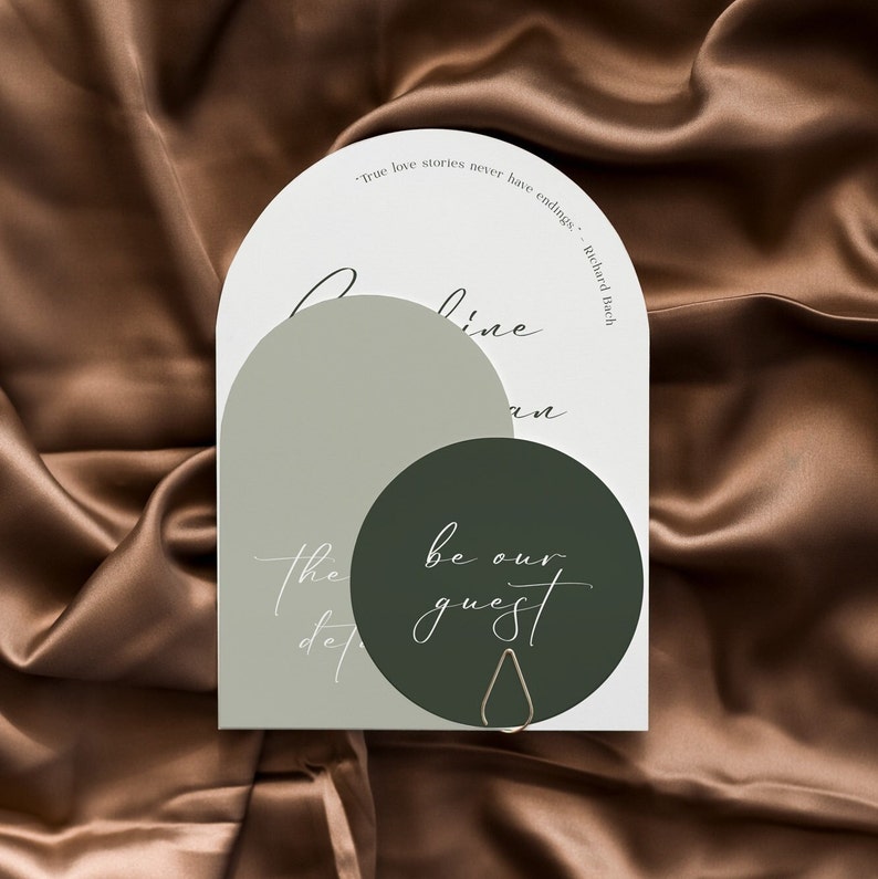 May include: A white arch-shaped card with green and gray circles. The text on the card reads "True love stories never have endings." - Richard Bach.  The text on the circles reads "be our guest".