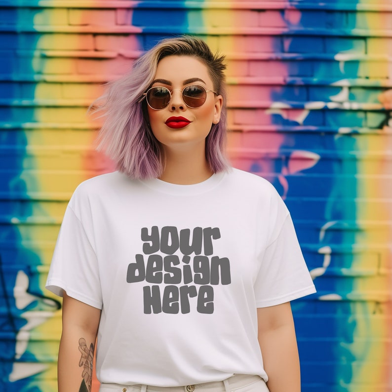 May include: A white t-shirt with the text "your design here" printed in gray on the front. The person wearing the shirt has purple hair and is wearing sunglasses.