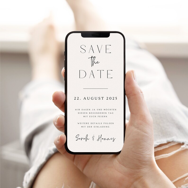 May include: A white save the date card on a smartphone screen. The card has black text that reads "Save the Date", "22. August 2025", "Wir sagen Ja und m&ouml;chten diesen besonderen Tag mit euch feiern", "Weitere Details folgen mit der Einladung", and "Sarah & Hannes".