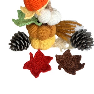 Peut inclure: Composition artisanale sur le thème de l'automne avec des citrouilles crochetées orange, jaune et marron, des courges blanches, des feuilles vertes et jaunes et des pommes de pin. Un objet décoratif pour l'automne.
