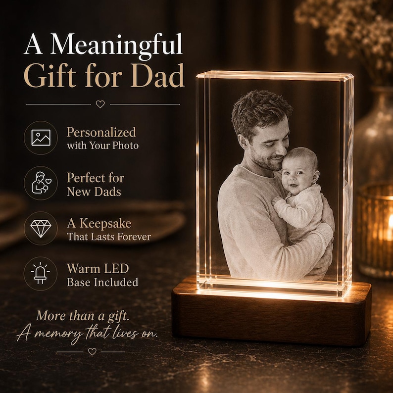 May include: A rectangular glass block featuring a laser-etched black and white photograph of an adult holding a baby. The glass sits on a dark brown wooden base that emits a warm LED light. Text on the left reads A Meaningful Gift for Dad.