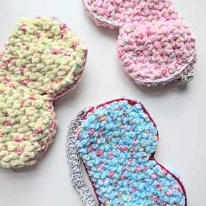 Pode incluir: Três máscaras de dormir feitas à mão em tons de rosa, azul e amarelo. As máscaras são feitas de um material macio e texturizado com um padrão salpicado de rosa e verde. Cada máscara tem uma borda contrastante e uma alça para prender.