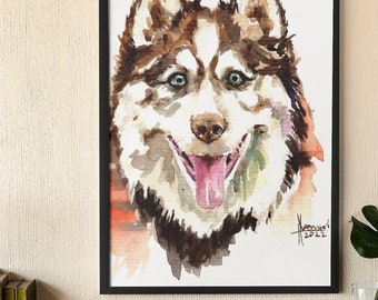 Może przedstawiać: Akwarela przedstawiająca brązowo-białego psa rasy husky z niebieskimi oczami. Pies uśmiecha się z wystawionym językiem. Obraz jest oprawiony w czarną ramę.