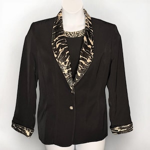 May include: A black blazer with a contrasting animal print collar and cuffs. The blazer has a single button closure and three-quarter length sleeves. The animal print features a mix of black and beige tones, adding a bold accent to the classic design.