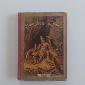 Op de afbeelding: Een vintage boekomslag met een rode rug en een bruine illustratie van een man met een papegaai, twee herten en een vuur. De titel van het boek is "Robinson der Jüngere".