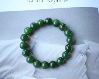 May include: A jade bracelet composed of round, polished green beads. The bracelet is displayed on a white surface with the text "Natural Nephrite" above it. The beads are a deep, rich green color.