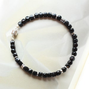 May include: A black beaded necklace with silver accents. The necklace has a magnetic clasp.