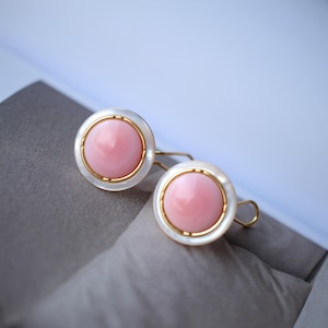 Può includere: Un paio di orecchini in opale rosa con montature in oro e dettagli in madreperla bianca.