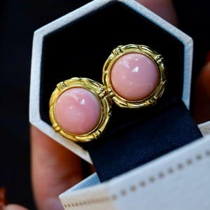 Può includere: Un paio di orecchini d'oro con pietre rotonde rosa incastonate in una cornice d'oro.