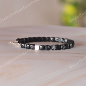 Op de afbeelding: Zwarte en witte edelsteen armband met een zilveren spacer bead. De armband is gemaakt van vierkante kralen.
