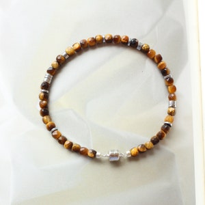 May include: A brown and gold tiger's eye beaded bracelet with a silver magnetic clasp.