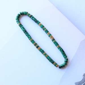 Op de afbeelding: Een groene en gouden kralenketting met een malachiet-steenontwerp.