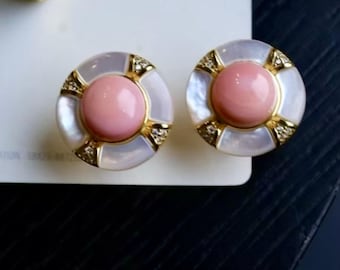 May include: A pair of round stud earrings. Each earring features a light pink center stone surrounded by a gold-toned frame and a white, iridescent outer ring. Small, clear stones are set into the gold frame.