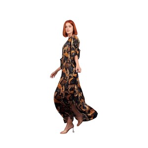 May include: A long, flowing dress with a leopard print design in black, brown, and gold. The dress features a split on the side and short sleeves. The model is wearing clear heels.
