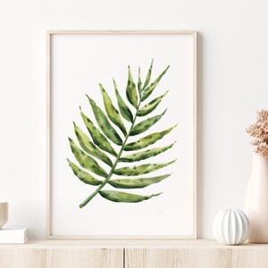 May include: A watercolor painting of a single green palm leaf on a white background. The leaf is depicted in a realistic style with detailed veins and a subtle texture.