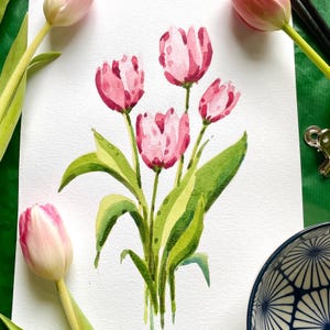 Può includere: Dipinto ad acquerello di un mazzo di tulipani rosa con foglie verdi su sfondo bianco.
