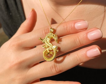 May include: A gold necklace with a detailed dragon pendant. The dragon is curled up with its wings spread out.