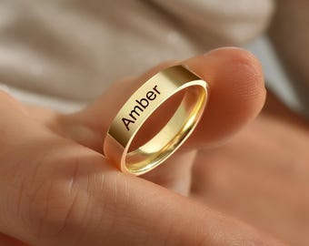 May include: A gold band ring with the name "Amber" engraved on it.