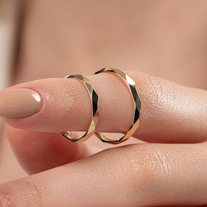May include: Two gold-toned rings with a faceted, geometric design. The rings are stacked on top of each other.