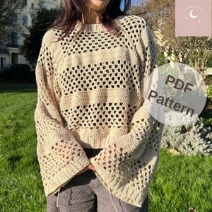 May include: A crochet sweater with a loose fit and bell sleeves. The sweater is made with a light beige yarn and has a delicate openwork pattern. The image includes the text "PDF Pattern".