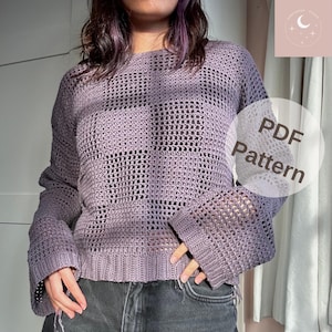 Könnte beinhalten: Ein lilafarbener Häkelpullover mit lockerer Passform und Glockenärmeln. Der Pullover hat ein "PDF Pattern"-Etikett am Ärmel.