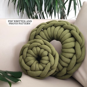 Könnte beinhalten: Zwei grüne gestrickte Donut-Kissen, eines größer als das andere, liegen auf einem weißen Sofa. Die Kissen sind aus dickem, gewebtem Stoff und haben eine weiche, plüschige Textur. Der Text "PDF WRITTEN AND PHOTO PATTERN" ist in der oberen linken Ecke des Bildes sichtbar.