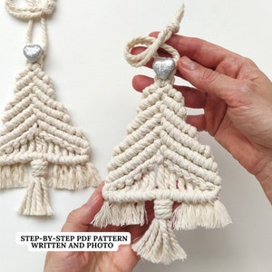 Op de afbeelding: Twee witte macramé kerstboomversieringen met zilveren hartversieringen. De versieringen zijn handgemaakt en hebben een franje detail. De tekst "STEP-BY-STEP PDF PATTERN WRITTEN AND PHOTO" is zichtbaar in de afbeelding.
