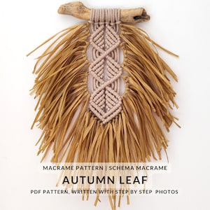 Pode incluir: Uma tapeçaria de macramé em forma de folha, com uma franja marrom clara e um centro rosa. O texto "MACRAME PATTERN | SCHEMA MACRAME AUTUMN LEAF PDF PATTERN, WRITTEN WITH STEP BY STEP PHOTOS" está na parte inferior da imagem.