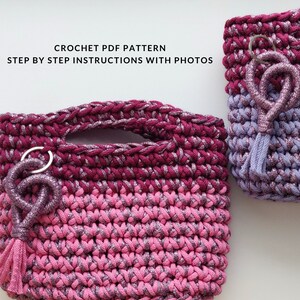 Può includere: Due borse all'uncinetto in filato rosa e viola scintillante. La borsa più grande ha un manico e un fiocco rosa. La borsa più piccola ha un fiocco viola. Entrambe le borse hanno un portachiavi argentato con un ciondolo rosa scintillante.
