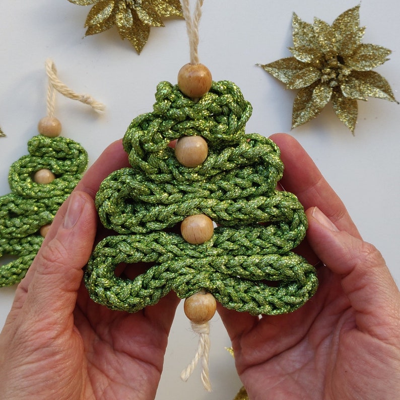 May include: A green yarn Christmas tree ornament with five wooden beads. The ornament is handmade and has a sparkly finish.
