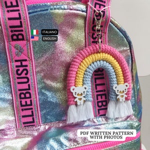 Peut inclure: Un porte-clés arc-en-ciel rose, jaune et bleu avec deux breloques d'ours blancs. Le porte-clés est attaché à un sac à dos rose avec les mots "Billie Blush" imprimés sur la sangle. Le texte "PDF WRITTEN PATTERN WITH PHOTOS" est imprimé sous le porte-clés.
