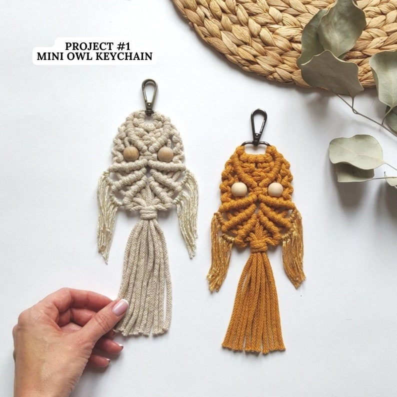 Peut inclure: Deux porte-cl&eacute;s hibou en macram&eacute;, l'un en beige et l'autre en jaune moutarde, avec des yeux en perles de bois.  PROJECT #1 MINI OWL KEYCHAIN est &eacute;crit en texte blanc sur fond noir.