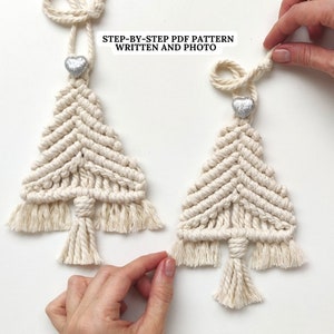 Peut inclure: Deux décorations de Noël en macramé avec des embellissements en forme de cœur argentés. Les décorations sont faites avec de la ficelle de couleur naturelle et ont une frange en bas. Le texte "STEP-BY-STEP PDF PATTERN WRITTEN AND PHOTO" est visible en haut de l'image.