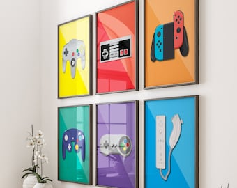 Puede incluir: Seis impresiones enmarcadas de diferentes mandos de videojuegos en una pared blanca sobre una mesa de madera con libros, una cesta y artículos decorativos. Los mandos son de diferentes consolas de juegos, incluyendo Nintendo, Sega y Playstation.